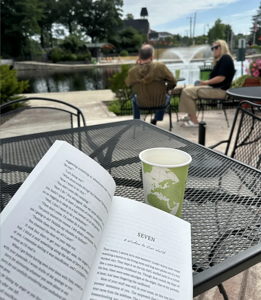 a reader reading a book with a hot cup of tea overlooking the mill pond in downtown brighton on a sunny summer day